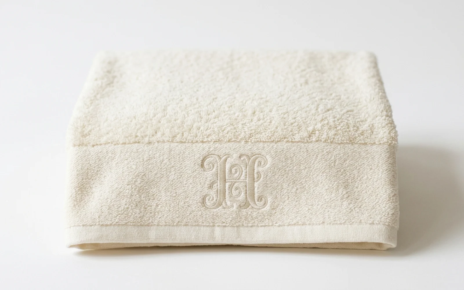 Serviette de bain en éponge écru pliée, monogramme brodé ton sur ton, à Paris