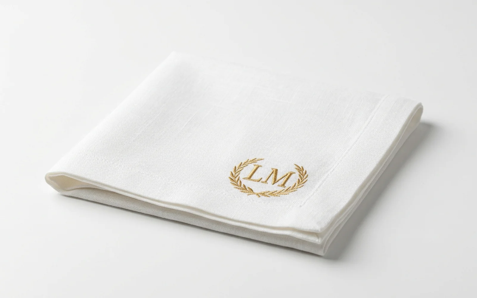 Serviette brodée d'un monogramme LM au laurier pour un mariage, atelier Paris