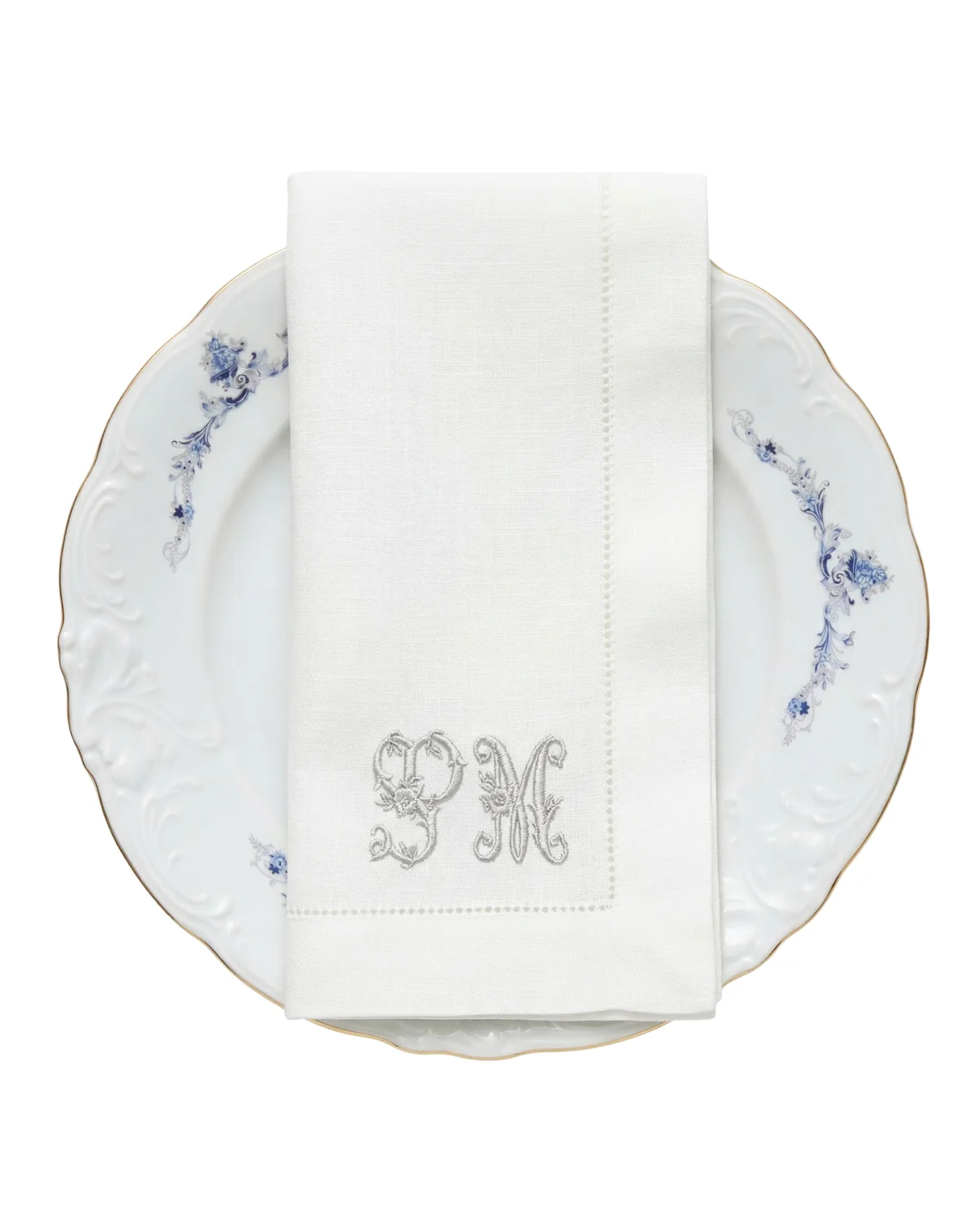Serviette de table monogrammée posée sur une assiette en porcelaine, dressage de réception