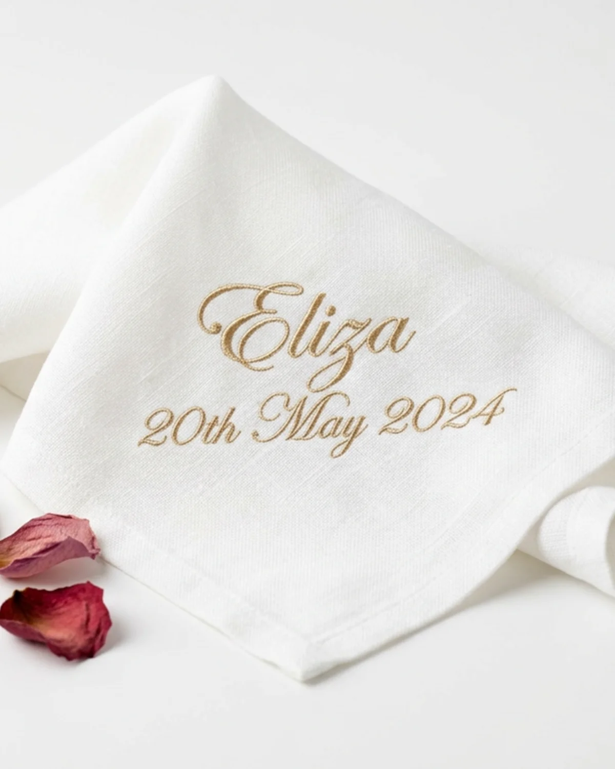 Serviette de mariage brodée du prénom d'un invité et de la date, posée en marque-place sur une assiette